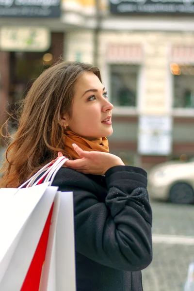 Woman walks along a city street with shopping bags — Stock Photo, Image