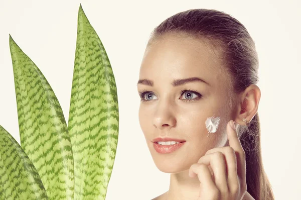 Girl smeared face cream. She is a three-quarters near the plant. — Stock Photo, Image