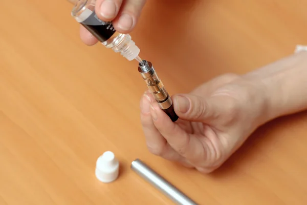 Female hands fill with liquid in the e-cigarette clearomizers — Stock Photo, Image