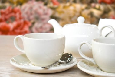 Restoranın arka planında beyaz fincan ve çaydanlık var. Masada bir çift çay. Metin için boşluk