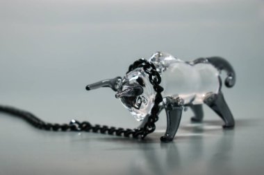 Boynunda siyah metal zincir olan bir boğa figürü. Gri arka plan. Zincire vurulmuş boğa. Seçici odaklanma. 2021 'in sembolü. Direniş konsepti, inatçılık, zorlukların üstesinden gelmek.