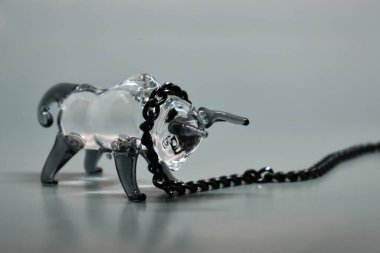 Boynunda siyah metal zincir olan bir boğa figürü. Gri arka plan. Zincire vurulmuş boğa. Seçici odaklanma. 2021 'in sembolü. Direniş konsepti, inatçılık, zorlukların üstesinden gelmek.