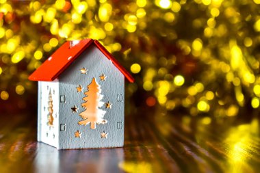 Noel dekoru. Bulanık bir arka planda parlak pencereleri olan, altın bokeh efektli bir ev şeklinde bir lamba. Noel kartı. Metin için yer
