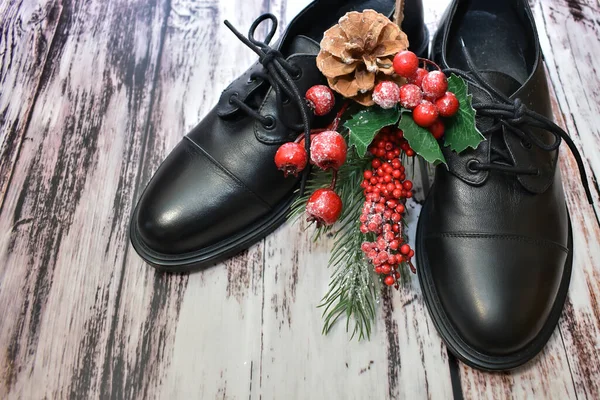 木製の背景に黒い革の靴とクリスマスの装飾 スタイリッシュな女性のブーツとスプルースの小枝のペアは ラミネートフロアにクリスマスのおもちゃで 革の靴のケア カスタム仕立て 靴の修理 — ストック写真