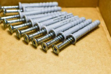 Karton kutunun altında bir grup çivi ve çukur var. Tamir için malzeme deposu. Beton tamiri için çeyiz. Bileşenler, hızlı kurulum. Karton kutudaki vidaları kendi kendine vuruyor.