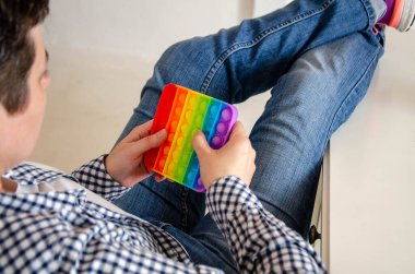 Elinde stres önleyici bir oyuncak tutan bir kadın. Gökkuşağı Meydanı Fidget Oyuncakları. Pop Bubble 'a tıklayın. Kadınların Ellerindeki gerilimi azaltmak için silikon oyuncaklar, Ofis sonrası dinlenme