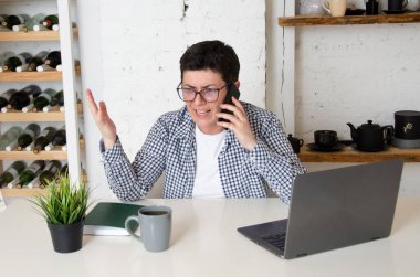Sinirli bir iş kadını, işvereniyle telefonda tartışıyor. Kısa siyah saçlı, gözlüklü bir kadın ofisinde oturmuş, duygusal olarak akıllı telefondan konuşuyor..