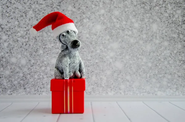 Netter Lustiger Spielzeughund Mit Weihnachtsmann Hut Sitzt Auf Rotem Geschenkkarton — Stockfoto