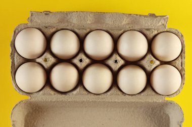 Açık karton bir kutuda beyaz tavuk yumurtaları ve sarıya izole edilmiş yumurtalar. Taze tavuk yumurtası. Kutudaki yumurtalar
