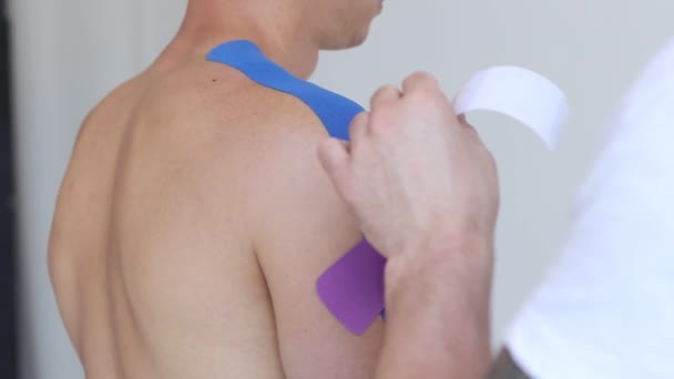 Физиотерапевт Накладывает Эластичную Терапевтическую Ленту Плечо Пациента Лечение Плеч Помощью — стоковое видео