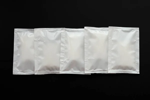 Boş beyaz kese paketleri siyah arka planda izole edilmiş. Boş hava geçirmez paket. Sos, kahve, ıslak mendil ve mayonez için maket..