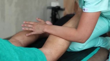 Bacağının alt kısmına masaj yapan tanınmayan bir kadın masörün yakın çekim elleri. Güçlü elleri olan profesyonel terapist ayak ve alt bacak masajı yapıyor.