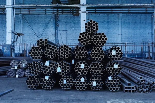 Tuberías de metal en un almacén. Pilas de tubos de acero redondos nuevos en fa — Foto de Stock