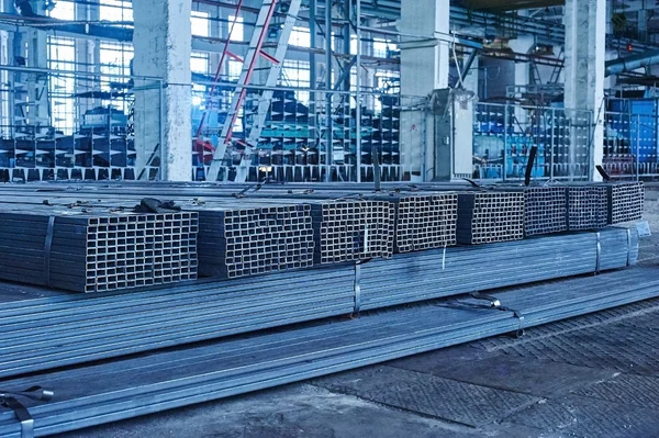 Metal pipes in a warehouse. Stacks of new square steel pipe in f — Stock Photo, Image