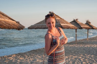 kumlu bir plaj boyunca yürüyen genç bir kadın