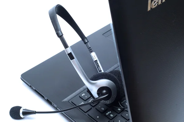 Auriculares acostados en un teclado de computadora portátil —  Fotos de Stock