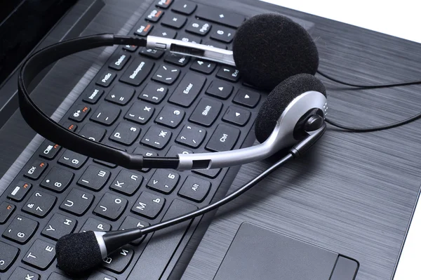 Auriculares acostados en un teclado de computadora portátil —  Fotos de Stock