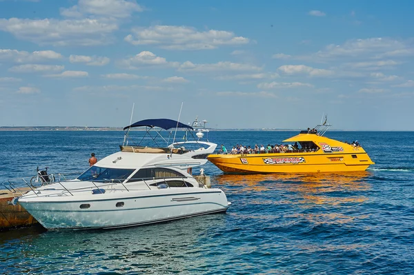 Turister sola, bada och koppla av på stranden har roligt. Vit motoryacht över piren i hamnen — Stockfoto