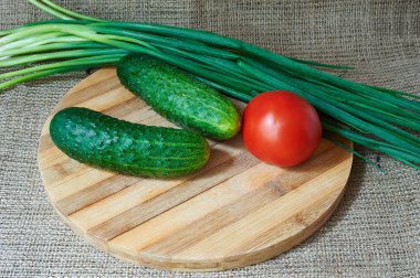 Taze kırmızı domates ve salatalık, bir ahşap tepsi yeşil soğan