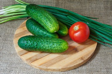 Taze kırmızı domates ve salatalık, bir ahşap tepsi yeşil soğan