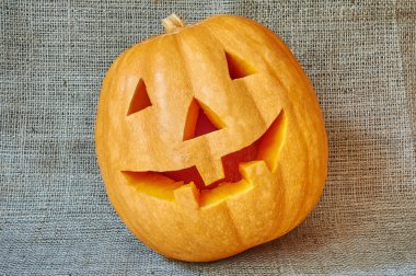 Halloween orange pumpkin on a burlap background in a rustic styl