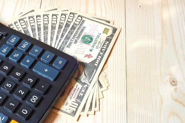 Calculator and dollars on a wooden background — Φωτογραφία Αρχείου