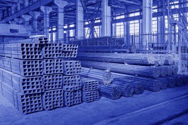 Metal borular bir depoda. Yeni kare ve yuvarlak çelik yığınları