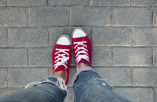 Women's feet in red sneakers — ストック写真