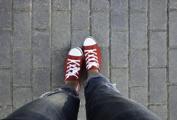 Women's feet in red sneakers — Stock Photo, Image