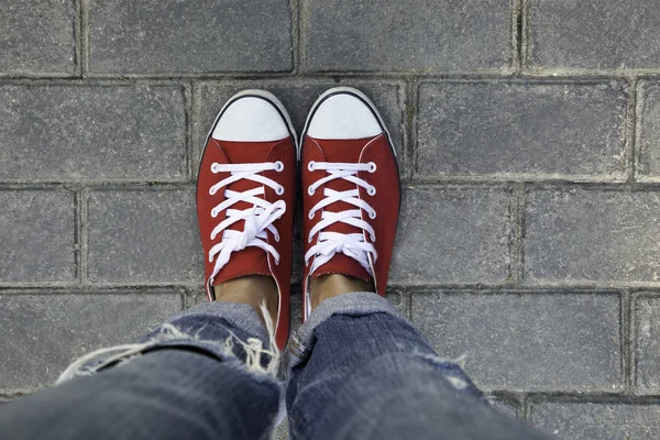 Women's feet in red sneakers Royalty Free Stock Images