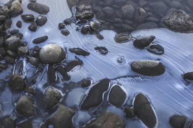Gölün donmuş yüzeyinde çakıl taşları.