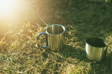Dağlardaki çayırlarda iki metal bardak. Yürüyüş konsepti..
