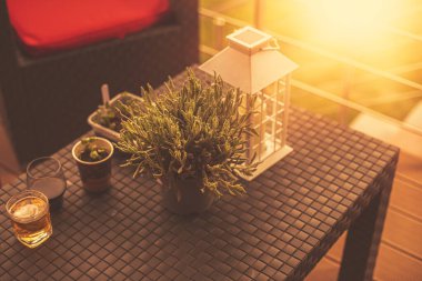 Masasında fener, bardak ve bitkiler olan modern bir teras..