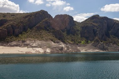 Huzurlu göl manzarası ve doymuş mavi renkler, dağlarla birleşmiş.