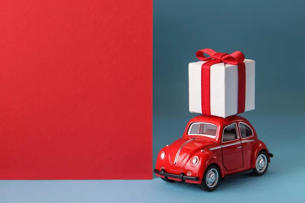 Czerwony samochód dostarczający prezenty świąteczne lub noworoczne na niebieskim tle. Święta Bożego Narodzenia. Przestrzeń kopiowania — Zdjęcie stockowe