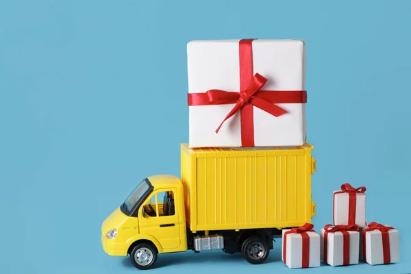 Yellow truck delivery gift box on blue background. Cargo transportation, delivery service. Transport company. Infrastructure and logistics. Unloading cardboard box. Copy space