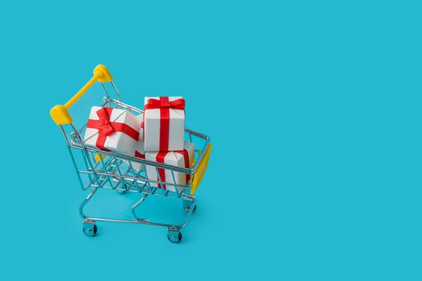 Winkelwagen met geschenkdoos op blauwe achtergrond. Online winkelen concept — Stockfoto