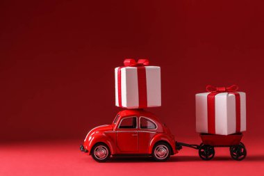 Kiev, Ukrayna, Ocak 03.2021: Kırmızı arka planda hediye kutusu teslim eden kırmızı araba. Sevdiğin kişi için sürpriz. Teslimat Konsepti Sevgililer Günü, Düğünler, Doğum günü, Baba veya Anne Günü