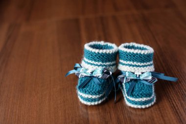 Ahşap arka planda el yapımı rahat çocuk ayakkabıları. Yeni doğanlar için örülmüş patik. Doğum ve annelik hazırlığı