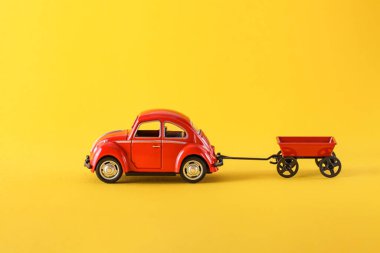 Kırmızı araba ve karavan sarı arka planda. Konsept Teslimat, lojistik. Alışverişe. Satılık. Sevgililer günü, düğünler, doğum günü, Noel, baba ya da anne günü. Boşluğu kopyala