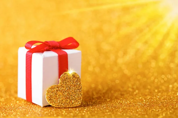 Złote serce i pudełko na brokatowym złotym tle Walentynki. Przestrzeń kopiowania — Zdjęcie stockowe