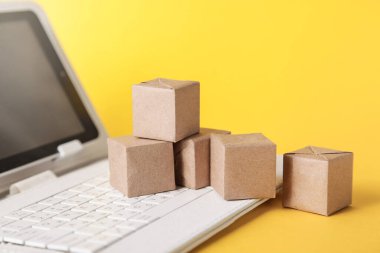 Çevrimiçi posta servisi. Karton kutular, sarı arka planda klavye. Teslimat hizmeti kavramı.