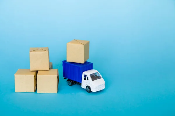 Carton boxes and blue truck on blue background. Cargo transportation, delivery service.