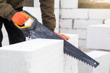 - Yakın çekim. İnşaatçı inşaat alanında elle testereyle havadan beton bloğu kesiyor. İnşaat, inşaat, el işi