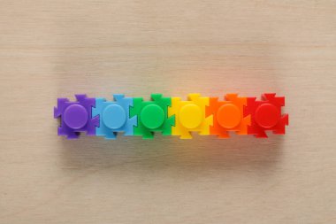 Ahşap arka planda gökkuşağı renginde çocuklar bulmaca çözer. lgtb bayrağı birleşti. LGBT. Gurur Ayı. Lezbiyen Gey Biseksüel Transseksüel. Aşk, insan hakları, hoşgörü.