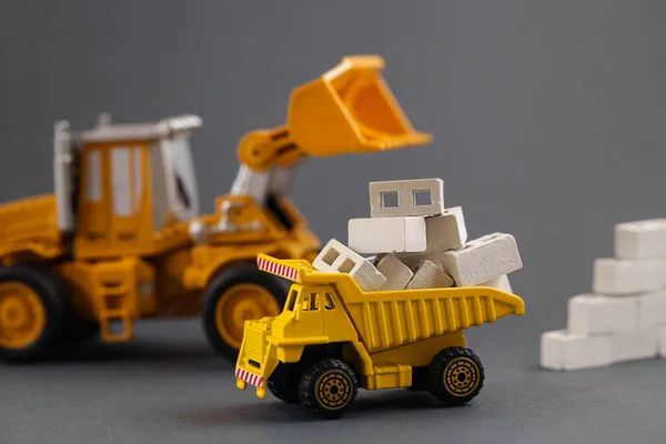Yellow Dump Truck, Excavator, building materials. Cargo Track, aerated concrete blocks. Delivery Building Material. Rent Construction Equipment. construction industry