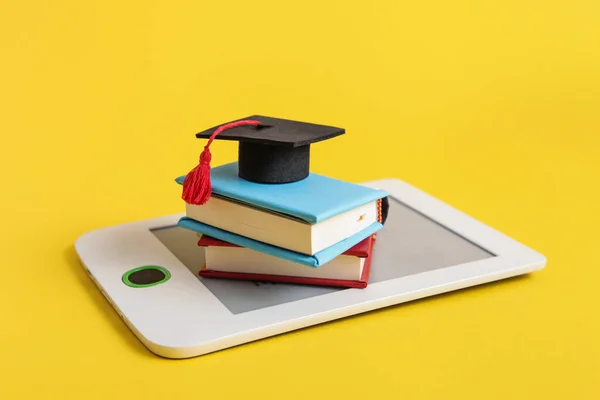 E-book, paper books, Square academic cap on yellow background. Education concept