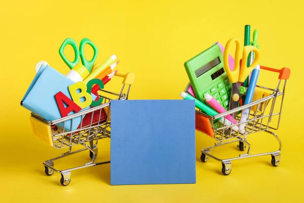 Educazione, Ritorno a scuola, Vendita, Shopping. Vuoto blu vuoto, Cancelleria, Carrello su sfondo giallo — Foto Stock