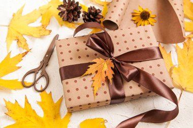 Hediye paketi. Kahverengi kağıt hediye kutusu ve beyaz üzerinde sarı kurumuş yapraklar. Sonbahar yaratıcı tatil hediyesi. Şükran Günü, sonbahar geçmişi.