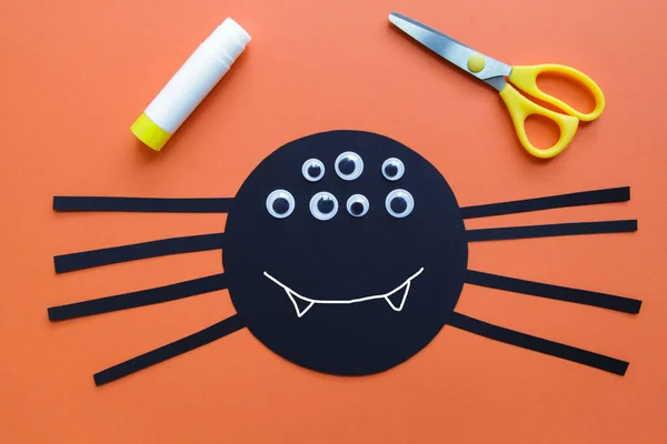 Child creates black spider. Halloween decoration. Children art project. DIY concept. Step-by-step. Step 6